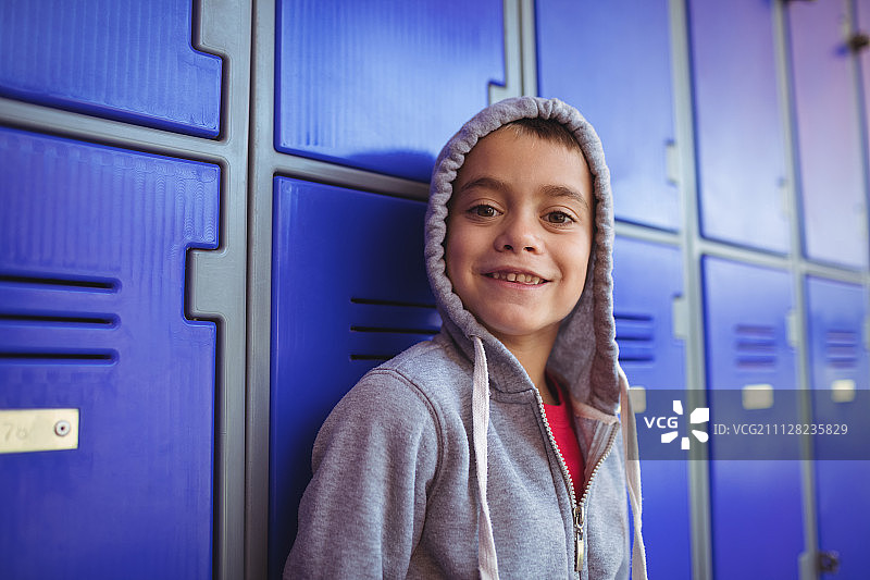 站在学校储物柜旁的微笑男孩肖像图片素材