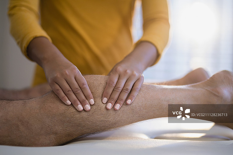 女理疗师在医院病房为老年男病人按摩小腿图片素材