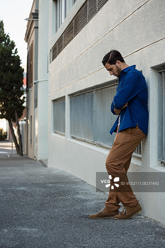 倚靠在墙上向下看的男人图片素材