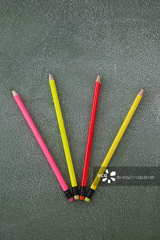 黑板上排列的带橡皮擦的彩色铅笔特写图片素材