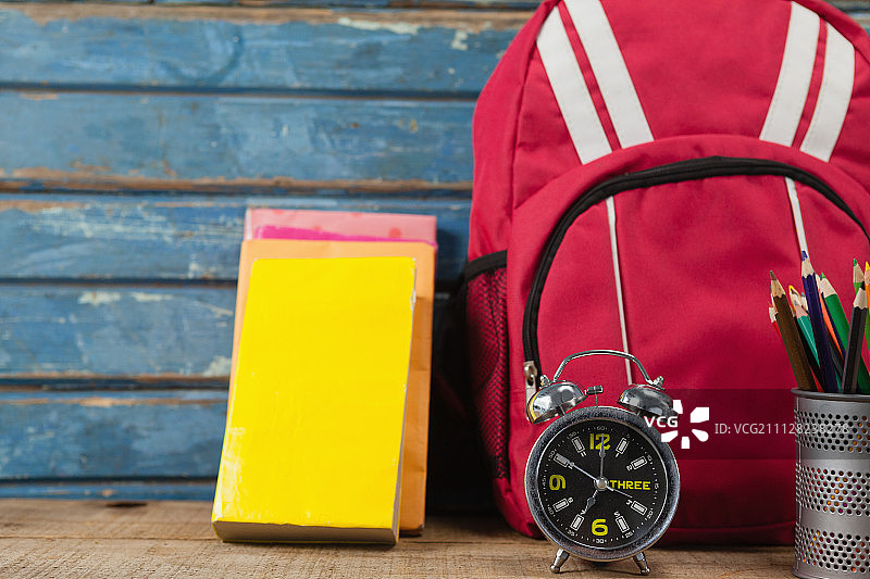 背包、书籍、闹钟和笔筒（蓝色木质背景）图片素材