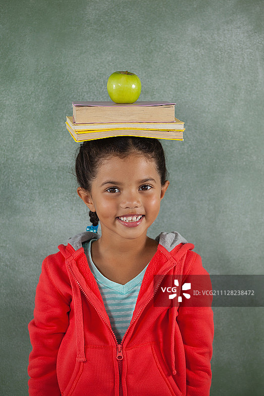 年轻女孩头顶着书和苹果的肖像图片素材