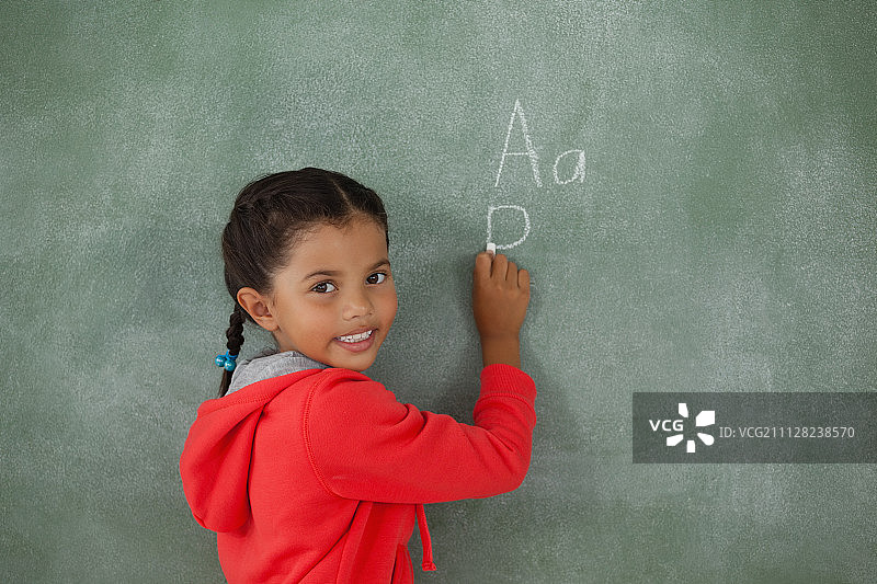 在黑板上写字的小女孩肖像图片素材