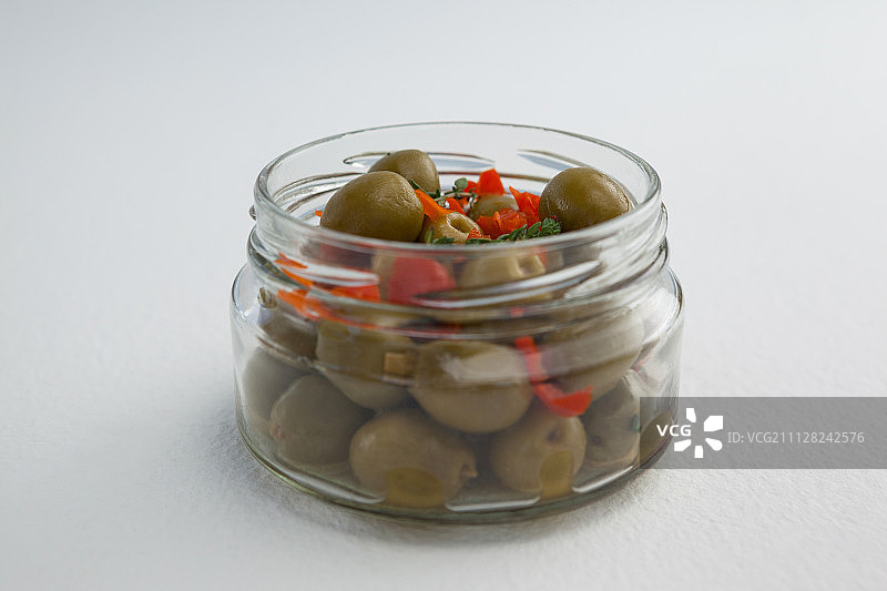 餐桌玻璃罐中绿色橄榄和香草特写图片素材