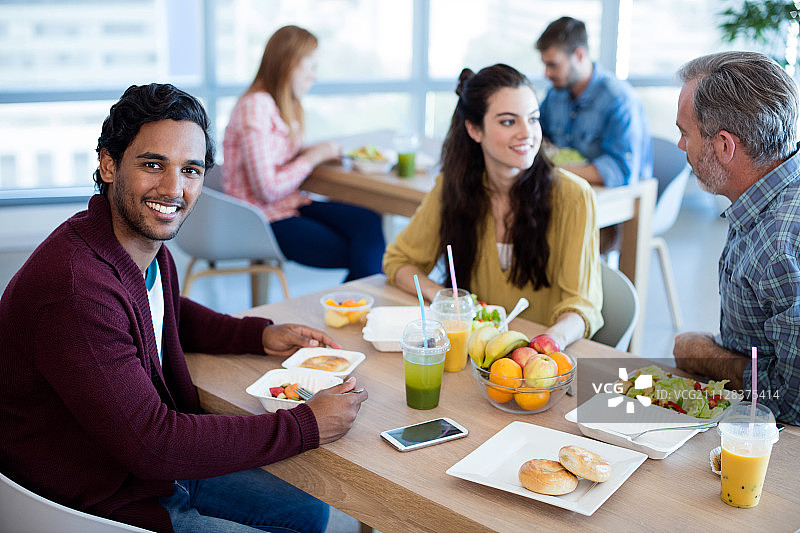 微笑的男人在办公室与同事共进午餐图片素材