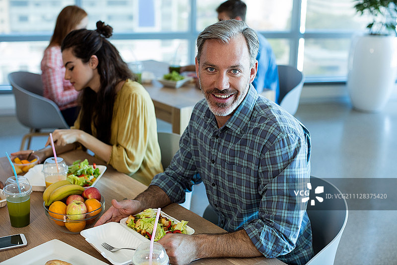 微笑的男人在办公室与同事共进午餐图片素材
