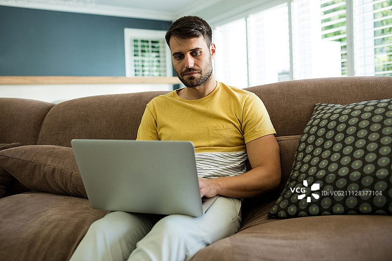 男人在家中客厅使用笔记本电脑图片素材