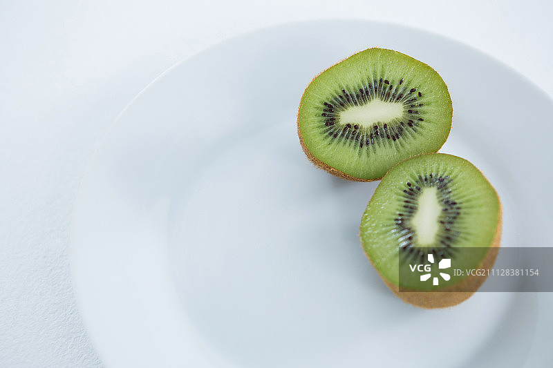 白色背景下盘中对半切开的奇异果特写图片素材