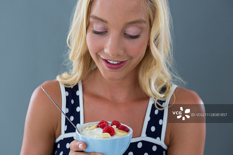 对着碗里的水果沙拉微笑的女人图片素材