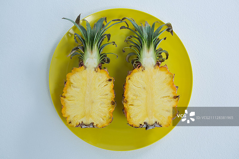 白色背景盘子里的两个半个菠萝俯视图图片素材