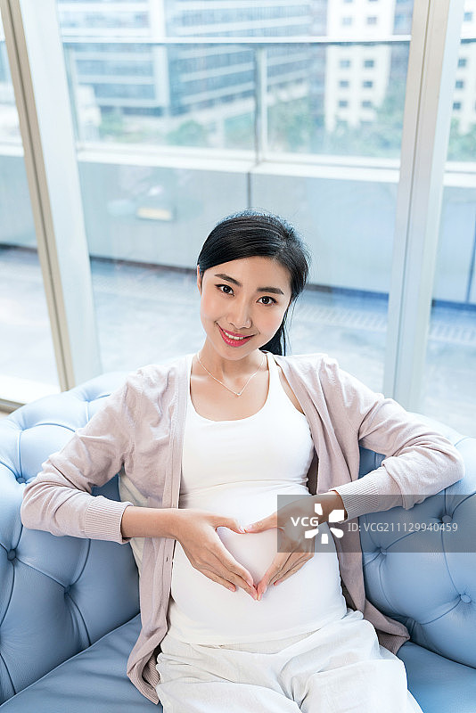 年轻孕妇坐在沙发上图片素材