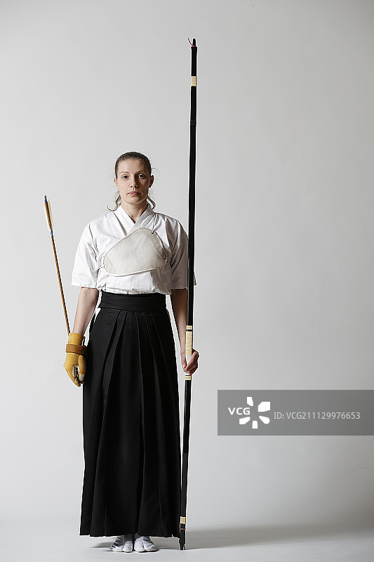 白人女子在白色背景上练习日本传统弓道图片素材