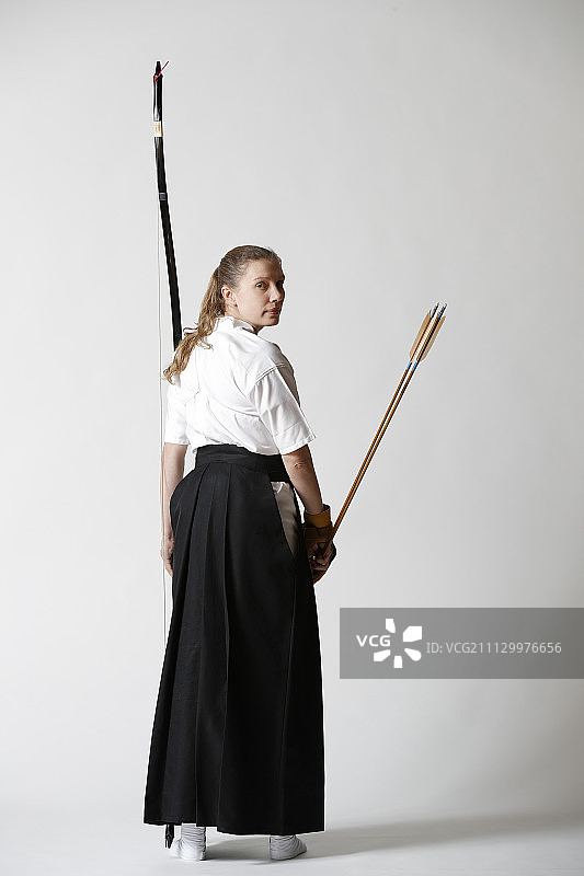 白人女子在白色背景上练习日本传统弓道图片素材