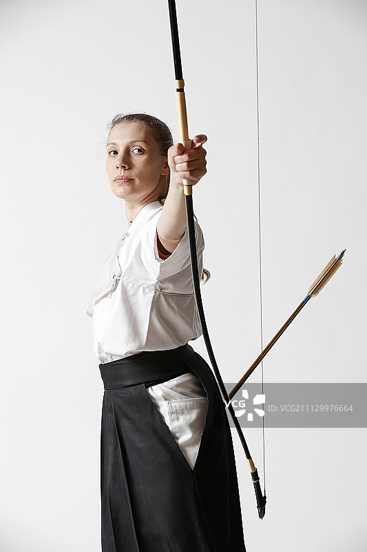 白人女子在白色背景上练习日本传统弓道图片素材