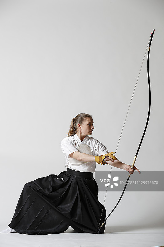 白人女子在白色背景上练习日本传统弓道图片素材