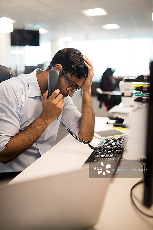 在办公室用固定电话交谈的紧张商人图片素材