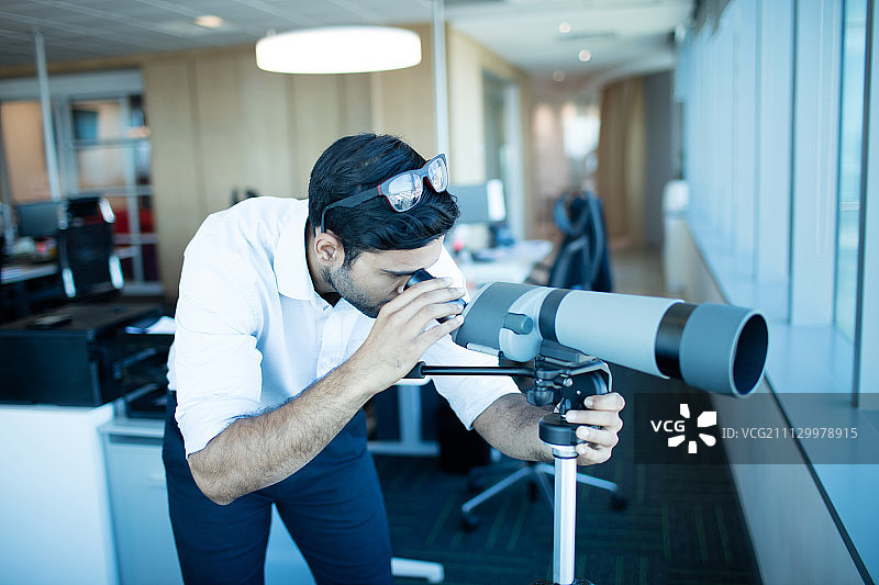 在办公室用双筒望远镜观察的商人图片素材