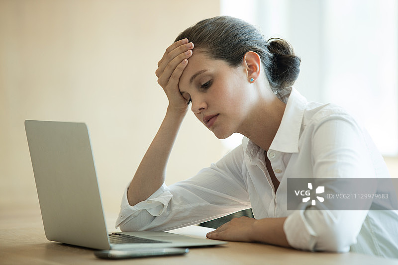 会议室内使用笔记本电脑的紧张女商人图片素材