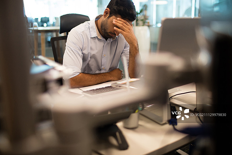 在办公室里手扶着头的焦虑的商人图片素材