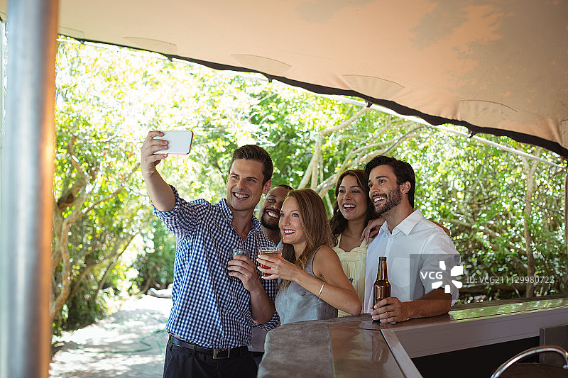 朋友们在餐厅吧台喝酒时自拍图片素材