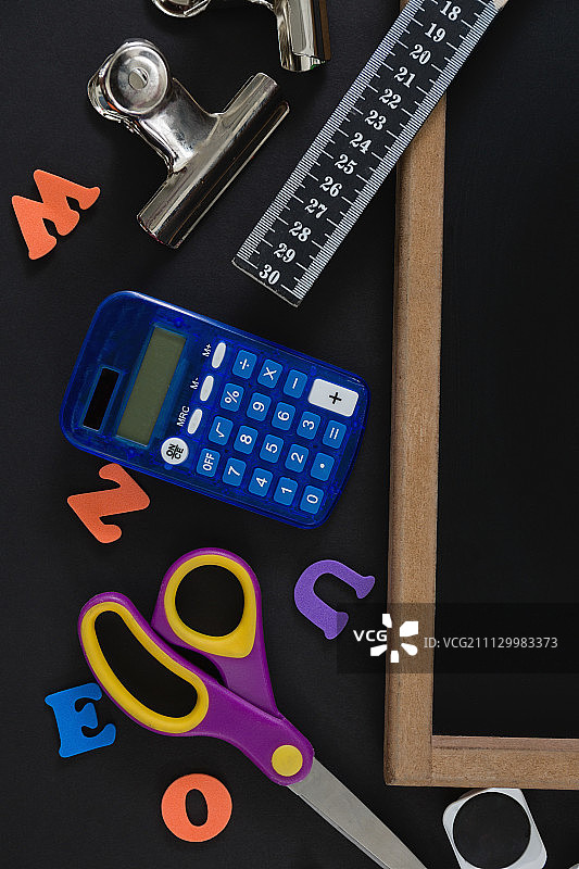 黑色背景上带有各种学校用品的空白石板特写图片素材