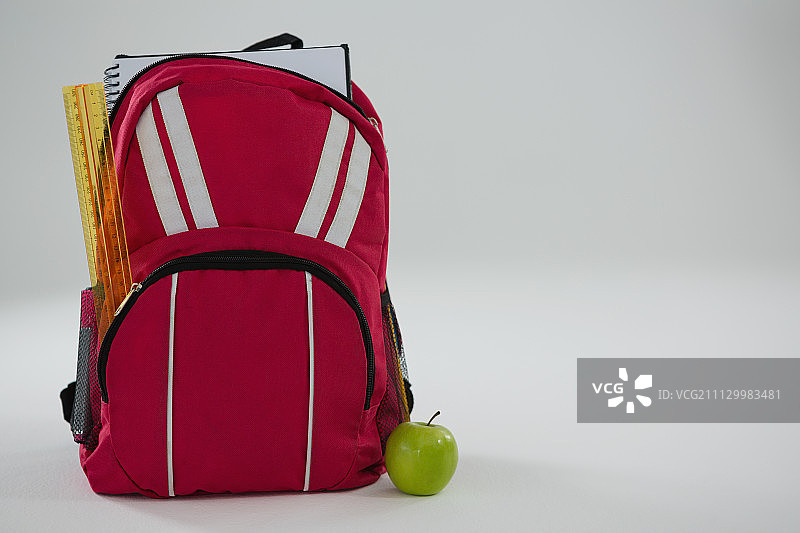 白色背景上的书包和学习用品、苹果特写图片素材
