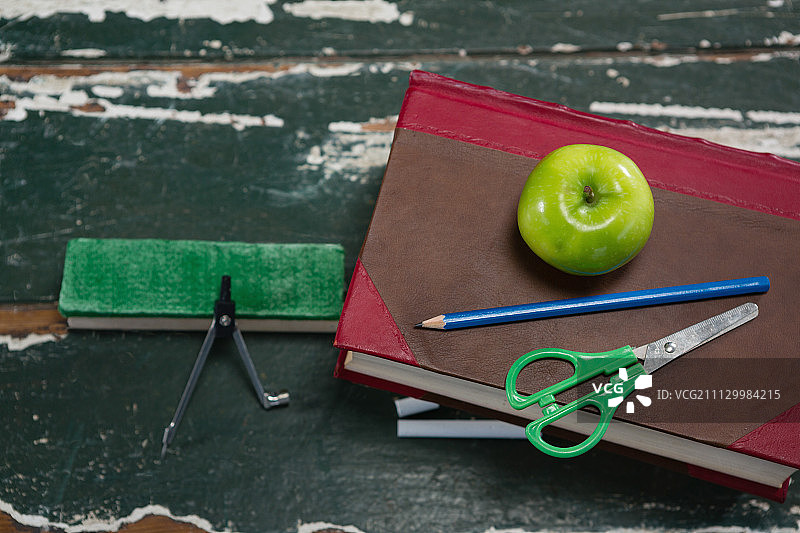 木桌上书籍和苹果旁的各种文具特写图片素材
