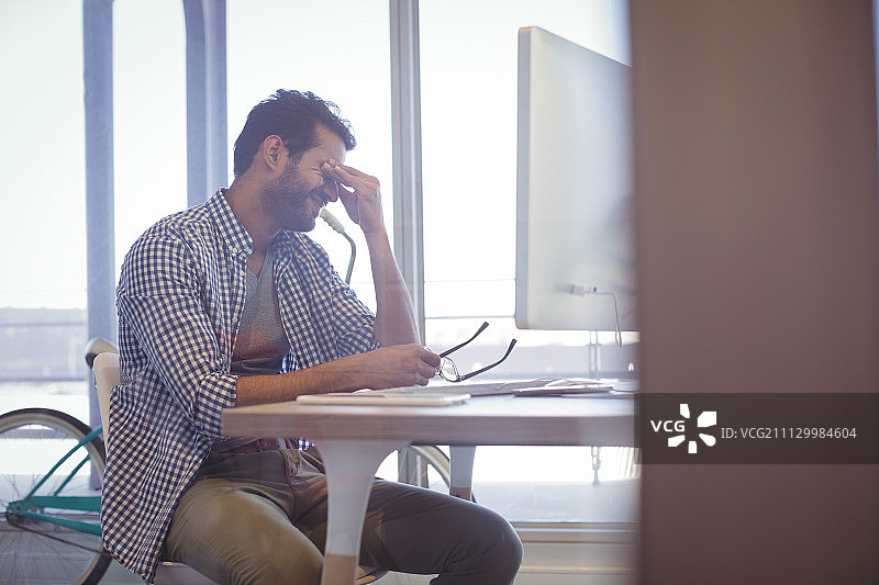 沮丧的商人坐在办公室的桌子旁图片素材