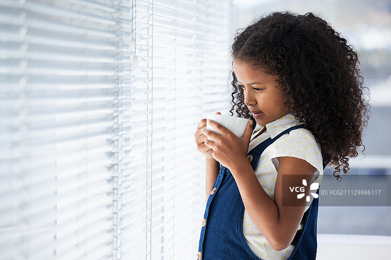 拿着咖啡杯站立的卷发商务女人图片素材