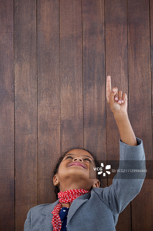 靠在木墙上，向上指的微笑商务女人图片素材