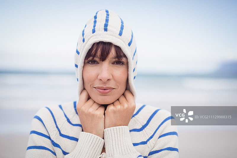 冬天在海滩上戴着连帽毛衣的女人图片素材
