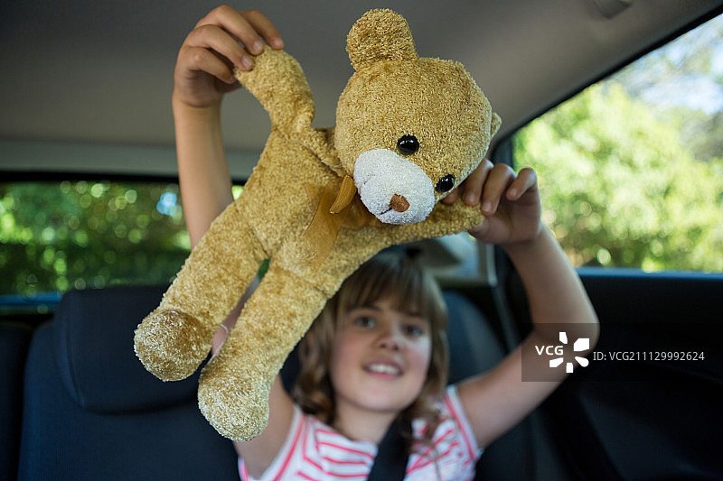 快乐少女在汽车后座玩泰迪熊图片素材