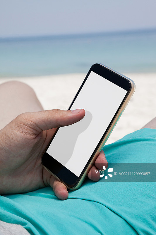 男子在海滩椅子上休息时使用手机图片素材