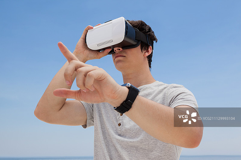 戴着VR头显，以蓝色天空为背景的男人特写图片素材