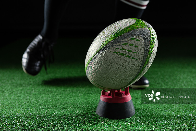 男性运动员在黑色背景下踢橄榄球的下半身图片素材
