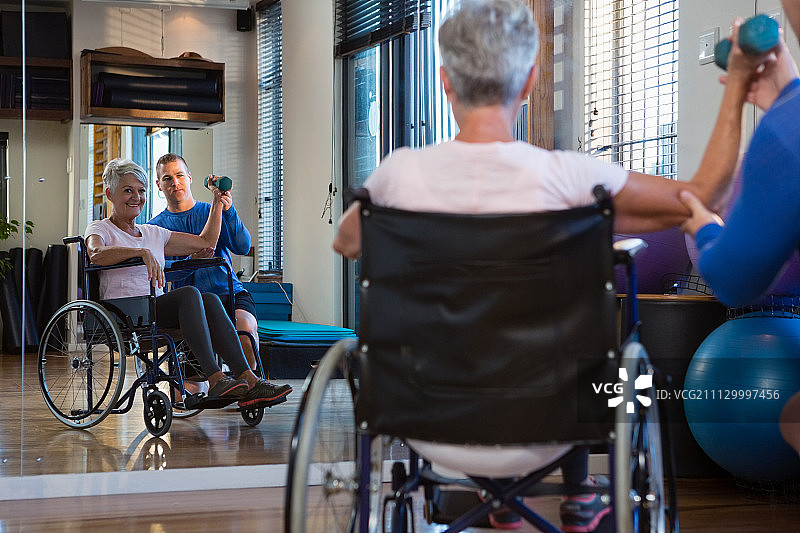 男理疗师帮助患者在诊所用哑铃进行锻炼图片素材