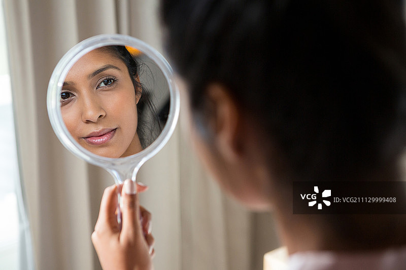 在家中用手镜反思的年轻女人图片素材