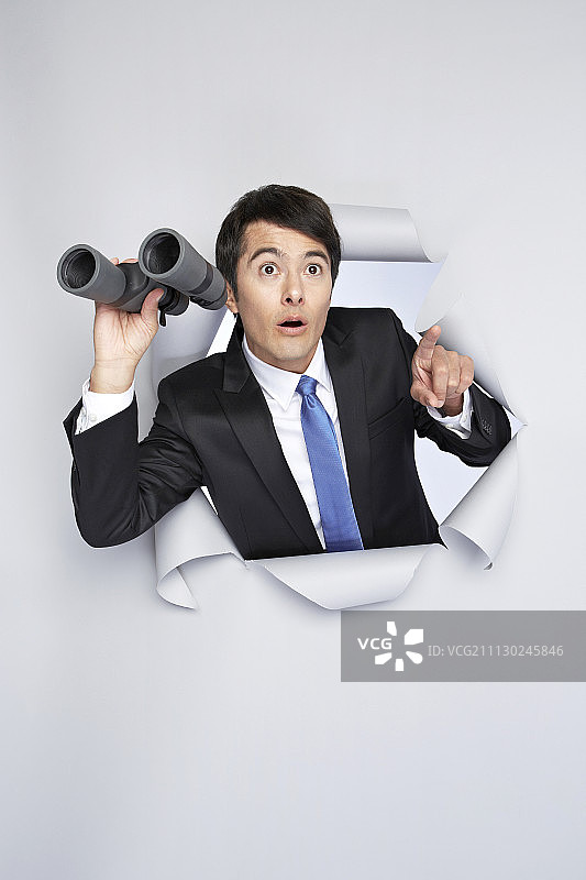 身穿西装的男人在白色背景下手持双筒望远镜并指向前方图片素材