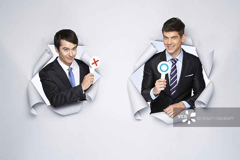 影棚拍摄穿西装的男人在白色背景前手持O和X标志图片素材