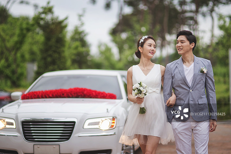 情侣穿着婚纱和西装走在婚车旁的摄影作品图片素材