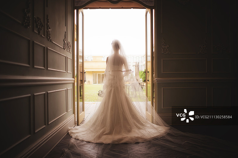 在敞开的门口戴着面纱的新娘的背影图片素材