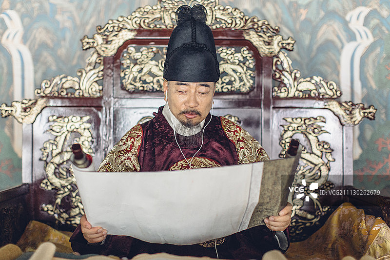 身穿韩国国王服装，听音乐看卷轴的年长男人图片素材