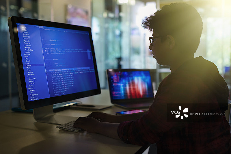 男学生在黑暗的教室里用电脑编程图片素材