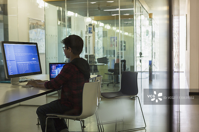 专注的男学生在黑暗的教室里用电脑编程图片素材