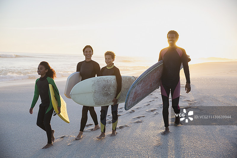 夏日海滩日落时分，家庭冲浪者携带冲浪板图片素材