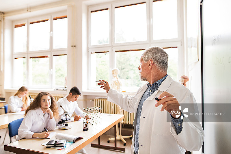 年长的教师给高中生讲授生物课图片素材