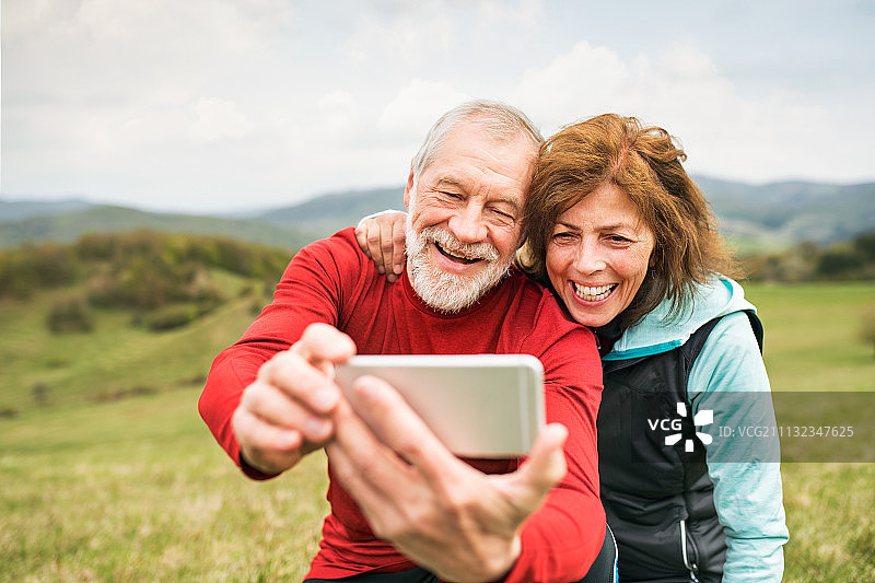 老年跑步者在户外用智能手机拍照图片素材