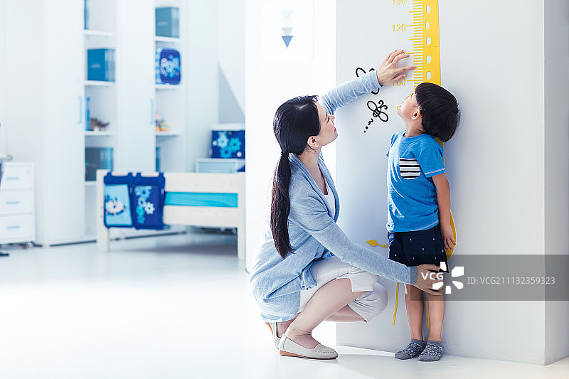 妈妈在为小男孩测量身高图片素材