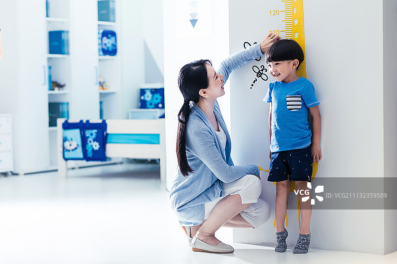 妈妈在为小男孩测量身高图片素材