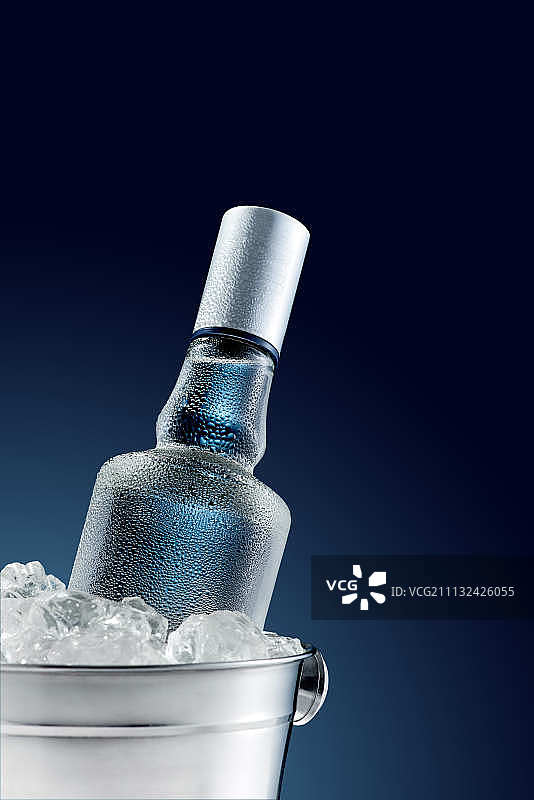 深色背景冰桶中的冰镇伏特加酒瓶图片素材